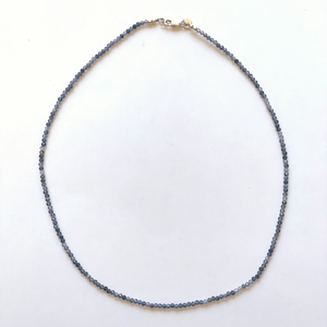 Beautiful, handcrafted 2.5mm round faceted Lolite semi-precious stone necklace; elegant on its own or personalize it with a pendant/charm; perfect for layering; adorned with .925 sterling silver Jai Style hand-embossed charm and lobster clasp; 20" length.