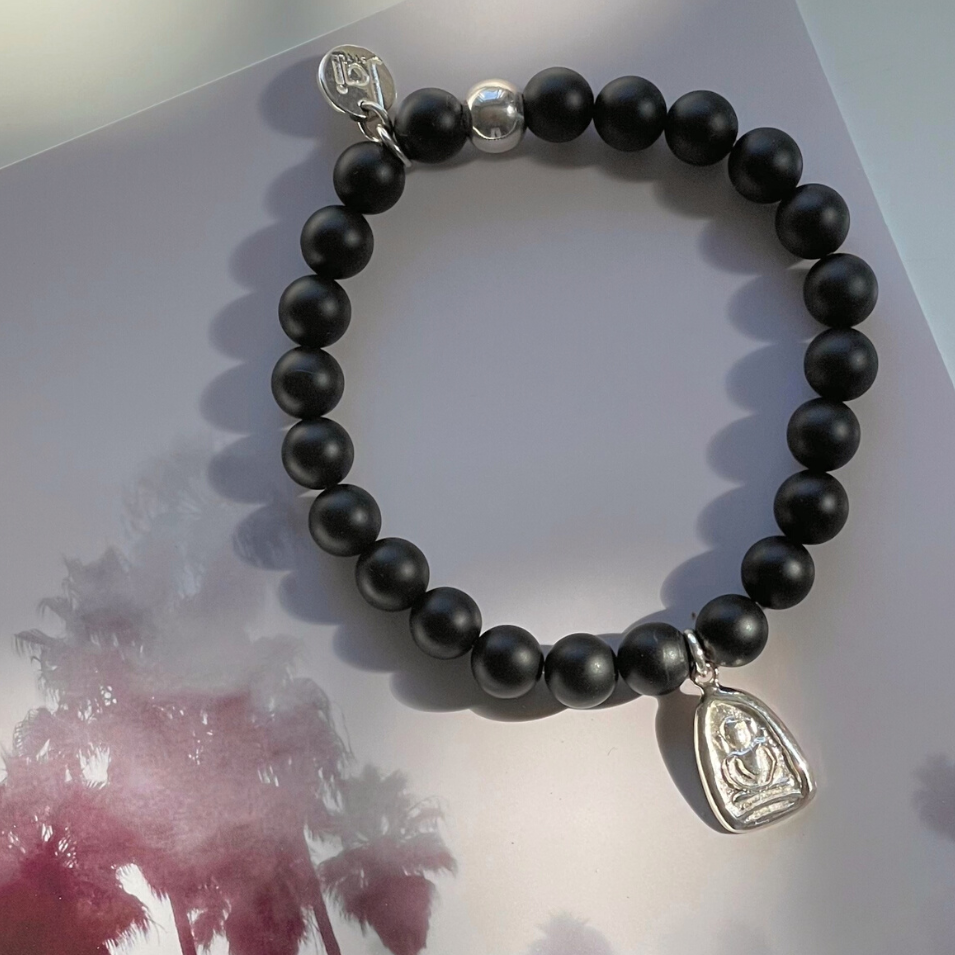 Beautiful 8mm matte black onyx gemstone bead bracelet with hand cast .925 sterling silver Thai amulet, Jai Style charm, and ball bead. Stretch bracelet measures 18.4 cm