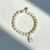 Beautiful 8mm cream riverstone bead bracelet with hand cast .925 sterling silver Thai amulet, Jai Style charm, and ball bead. Stretch bracelet measures 18.4 cm
